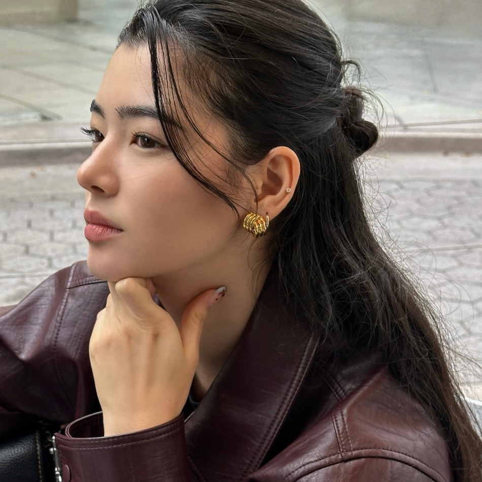 Woman wearing gold earrings with a blurred background