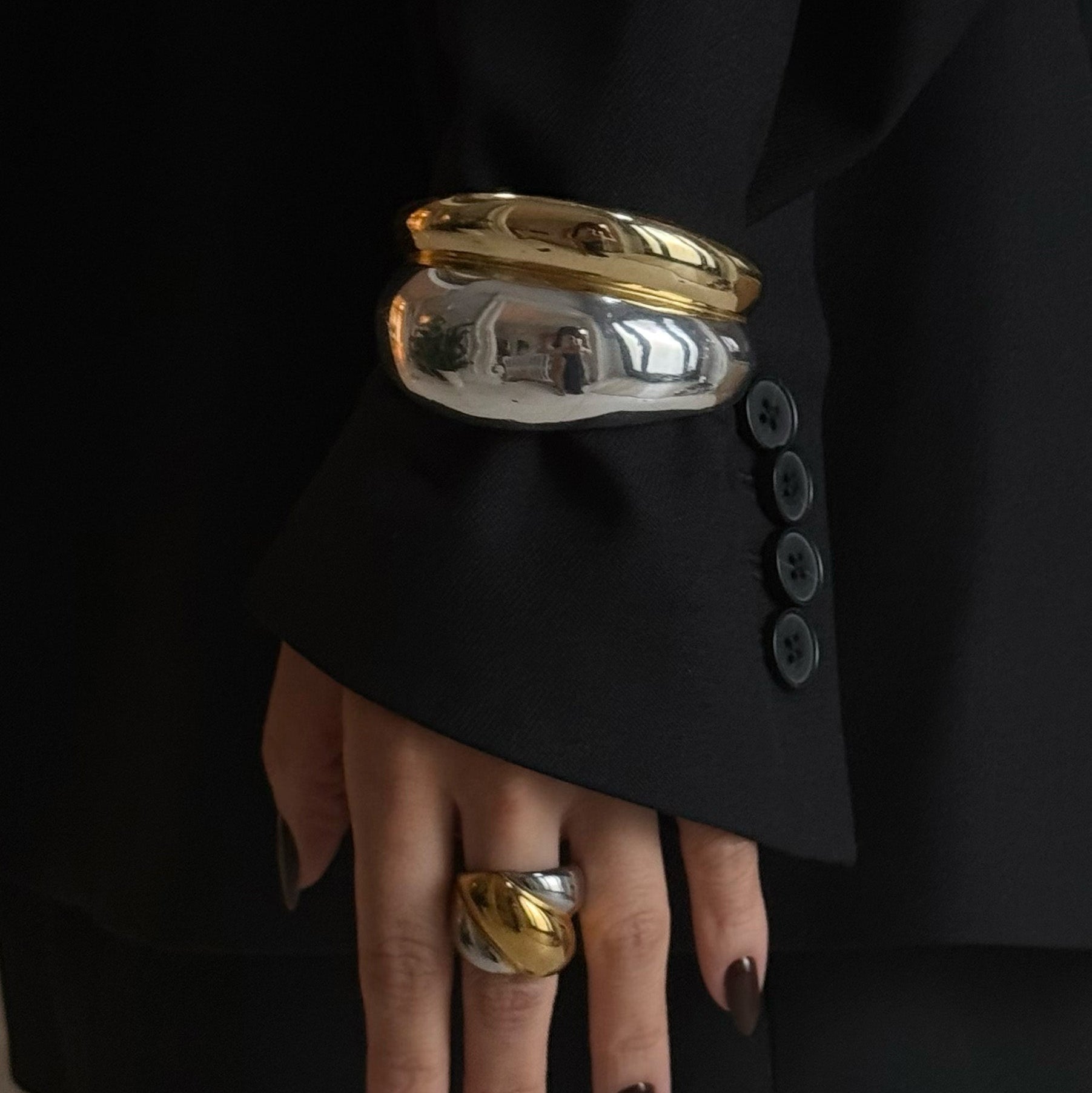 Gold and silver bangles on a hand with a black background