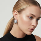 Close-up of a woman wearing silver earrings with a neutral background