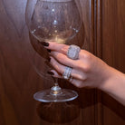 Hand holding a wine glass against a wooden background