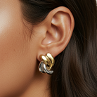 Close-up of a woman wearing gold earrings with a neutral background