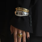 Gold and silver bangles on a hand with a black background